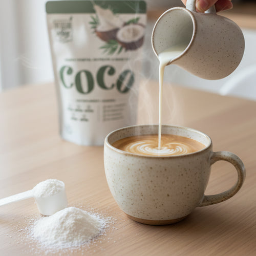 Sirviendo leche de coco VegganWay preparada en un café latte, con el envase del producto y una cucharada de leche de coco en polvo de fondo